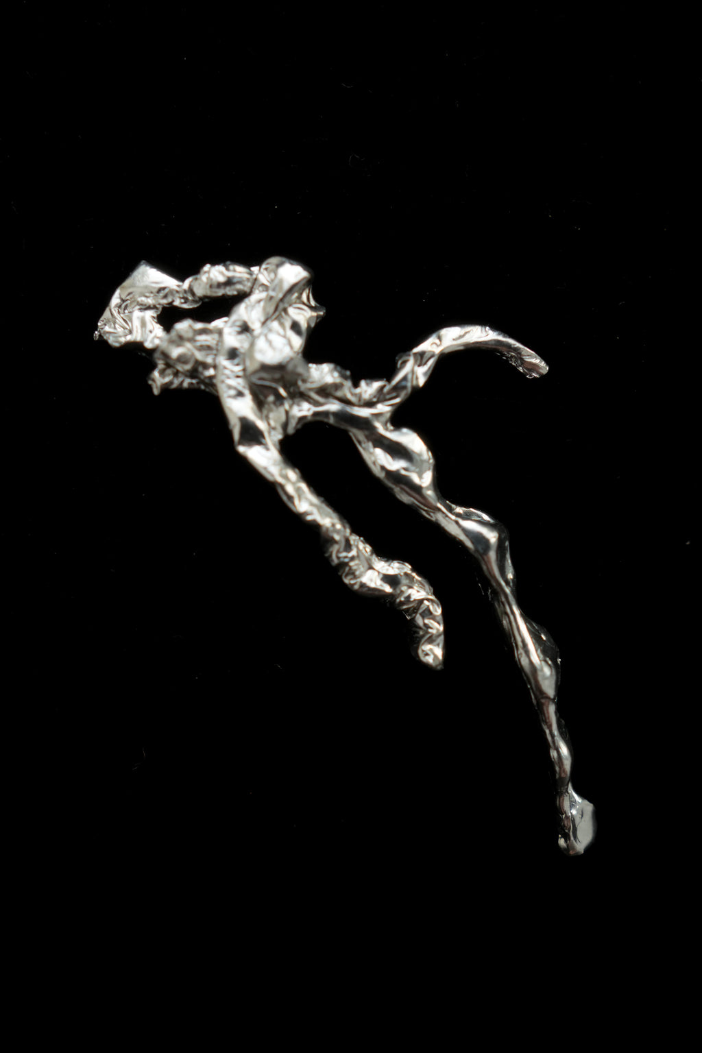 A highly textured, organic-shaped silver pendant or decorative sculpture with a polished metallic finish, set against a solid black background.